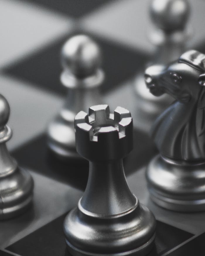 Close-up of silver metal chess pieces on a board, emphasizing strategy and competition.