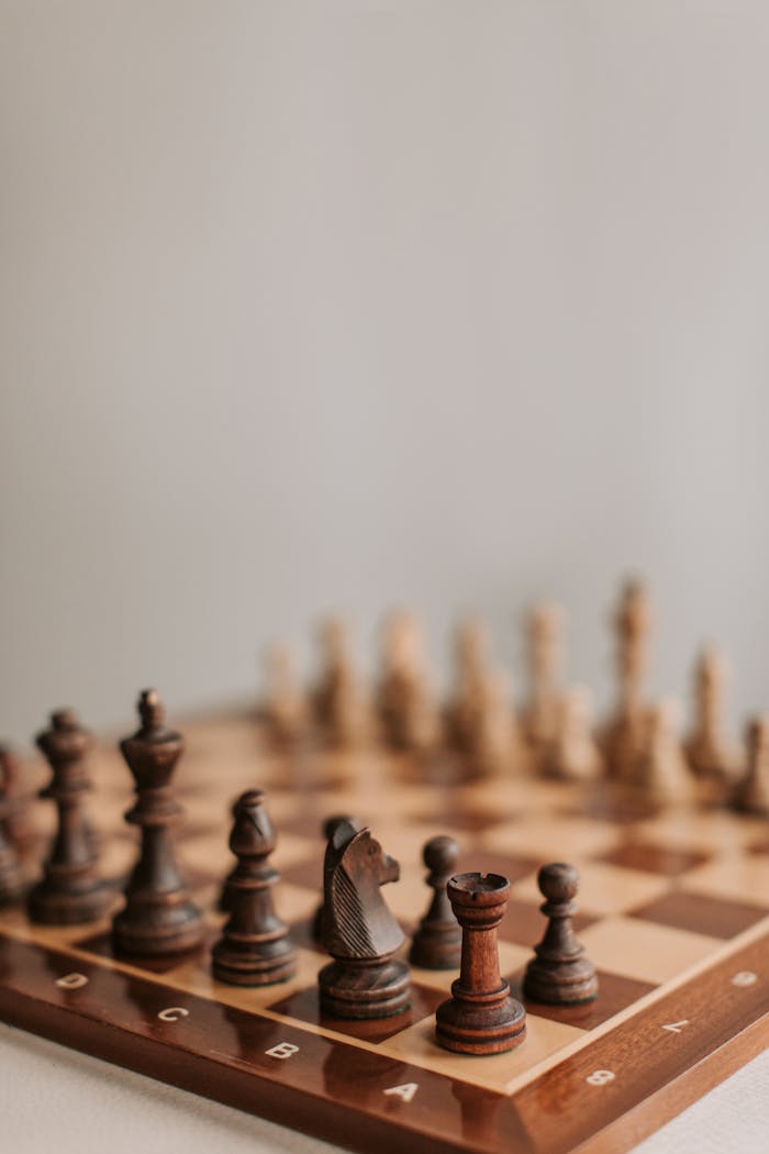 Close-up of arranged chess pieces on a chessboard highlighting strategy and focus.